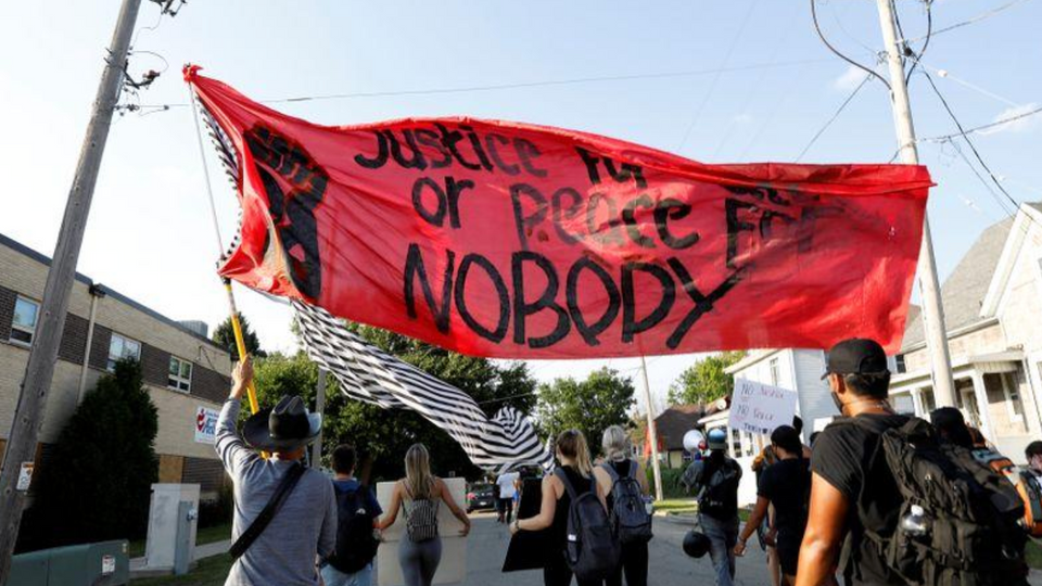 أشخاص يرفعون لافتة خلال احتجاج على إطلاق الشرطة الرصاص على جاكوب بلاك الأمريكي الأسود في ولاية ويسكونسن
