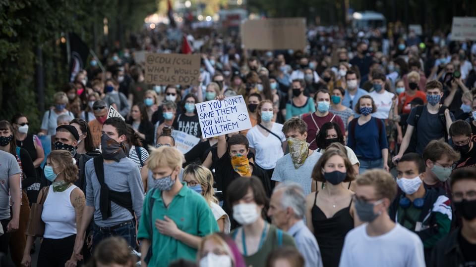 رفع حوالي 5000 شخص، وهم يضعون الكمامات تماشياً مع قواعد مكافحة انتشار فيروس كورونا، لافتات عليها شعارات مثل 